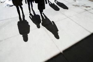 Students cast shadows on the pavement on a sunny winter day on the UW–Madison campus.