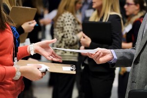 A student hands a recruiter a resume at the Spring Career and Internship Fair at the Kohl Center.