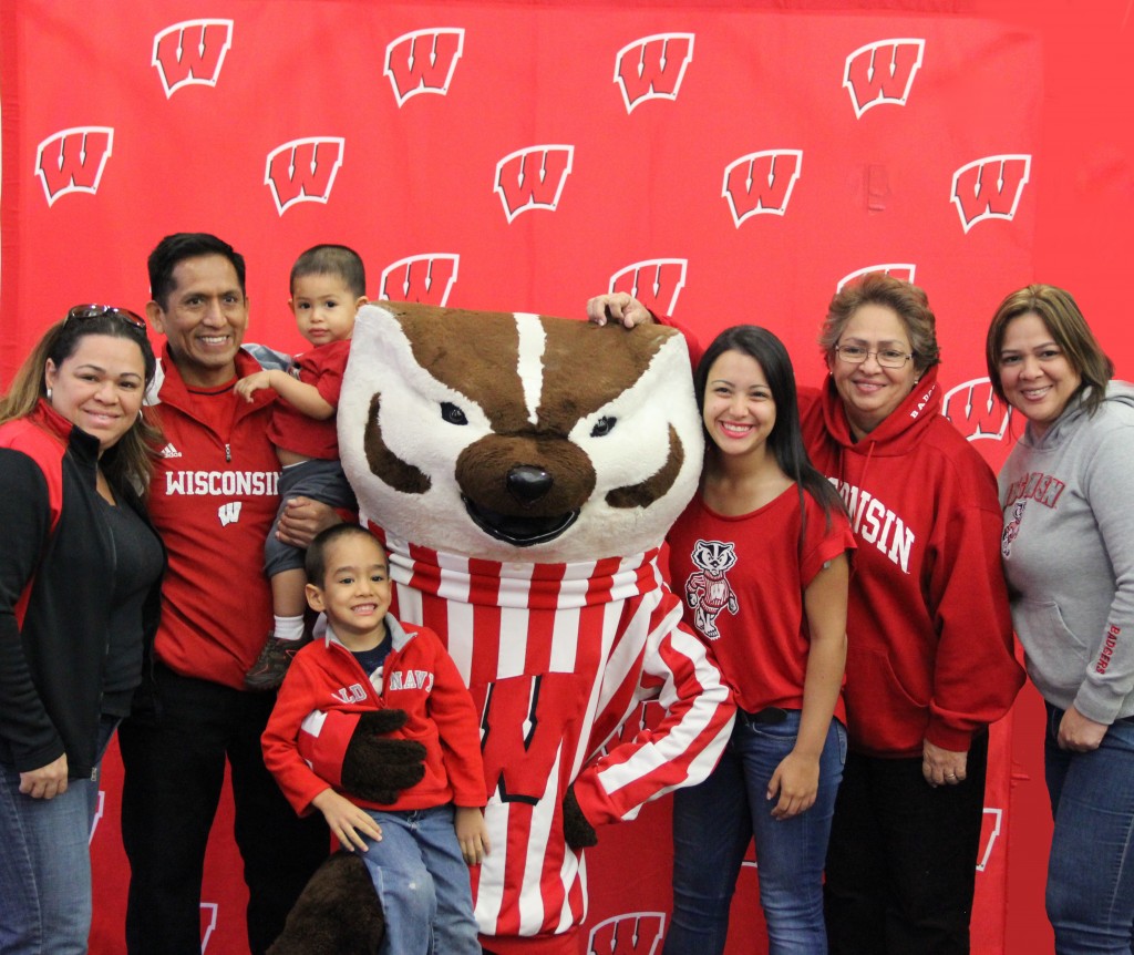 A family smiles big with Bucky Badger