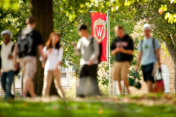 Pedestrians make their way along a sidewalk on Bascom Hill.