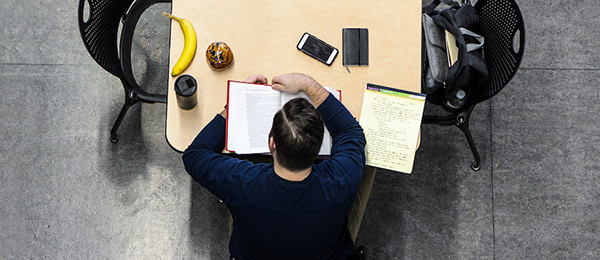 Seen in an overhead view, a student settles in for a morning of snack-fueled studying in the student lounge and atrium of the Law School Building.
