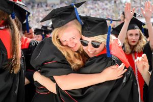 Two graduates share an emotional hug at the conclusion of a UW–Madison spring commencement ceremony at Camp Randall Stadium.