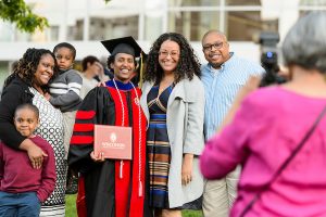 A graduate poses with her family following spring commencement.