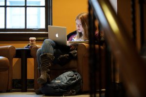 Seated in an armchair, an undergraduate student works on her laptop computer while enjoying the quiet of a tucked-away spot in a staircase landing at the Memorial Union.