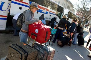 Getting ready to depart for spring break, a student organizes her luggage as others board two Van Galder buses parked in front of Memorial Union.