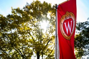 A W crest banner flutters in front of trees on Bascom Hill at the University of Wisconsin-Madison