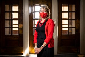 Vice Chancellor for Student Affairs Lori Reesor, wearing a red sweater and mask to match, in Bascom Hall.