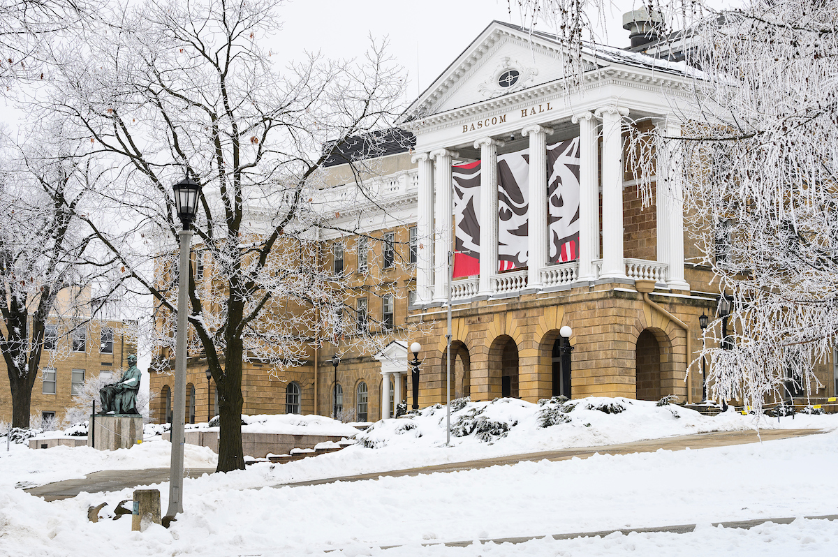 Rime ice coats the branches of trees flanking Bascom Hall on snow-covered Bascom Hill at the University of Wisconsin-Madison during a foggy winter day on Jan. 6, 2021. In between the building’s columns hangs a three panel graphic of UW-Madison mascot Bucky Badger. Unlike hoarfrost – which typical forms on clear, cold nights – rime ice forms when moisture in the foggy air coats nearby surfaces and freezes. (Photo by Jeff Miller / UW-Madison)