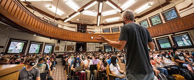 A lecturer gestures while teaching Chemistry 103 in a lecture hall in Agricultural Hall.