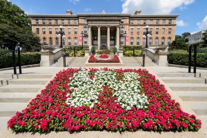 Contrasting red and white flowers form the letters U and W in flowerbeds leading to the entrance of Agricultural Hall on the UW-Madison campus.