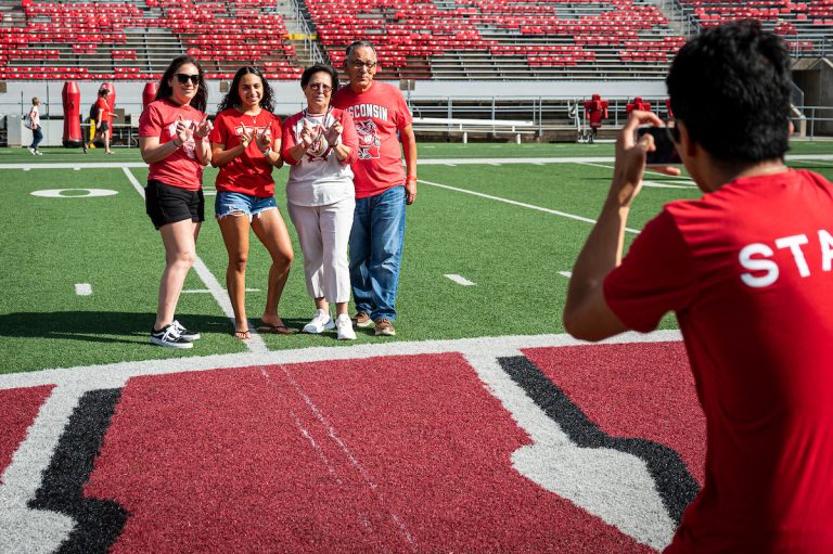 A UW student, along with her mother and grandparents, pose for a photo on the motion W on the 50-yard line of Camp Randall Stadium.