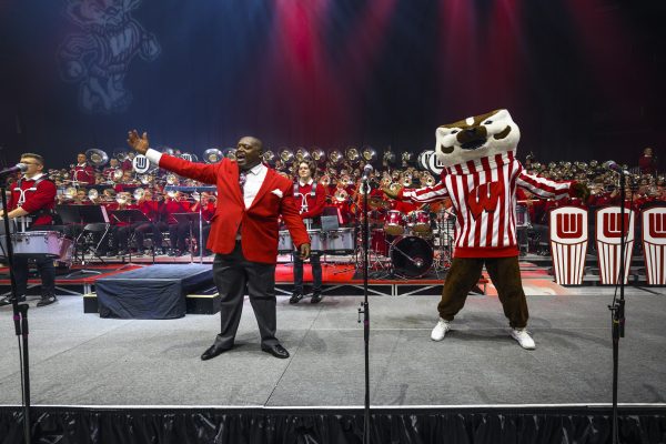 Corey Pompey and UW mascot Bucky Badger wave to the crowd during the UW Varsity Band Spring Concert in the Kohl Center at the University of Wisconsin–Madison