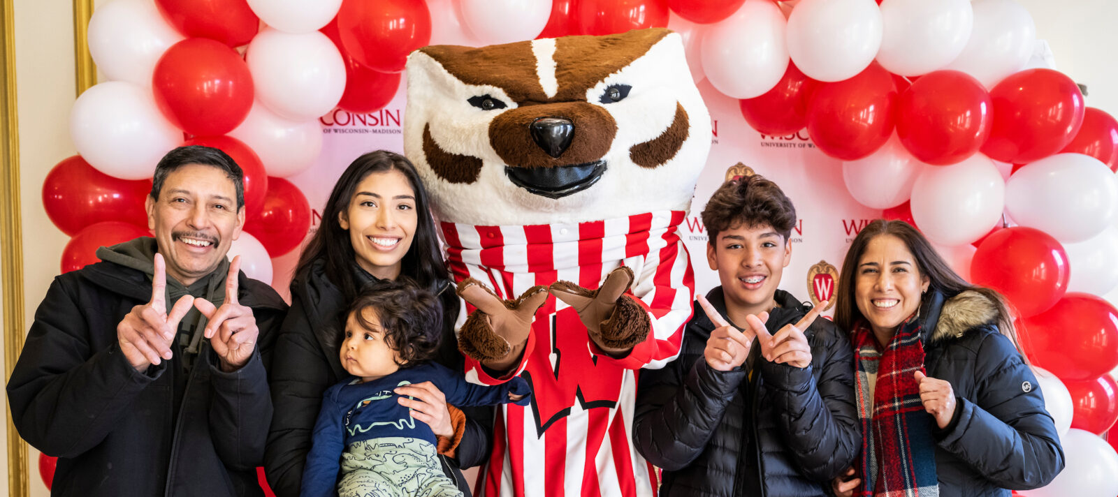 UW–Madison mascot Bucky Badger poses for a photo with UW–Madison senior Karen Bobadilla (second from left) and her extended family
