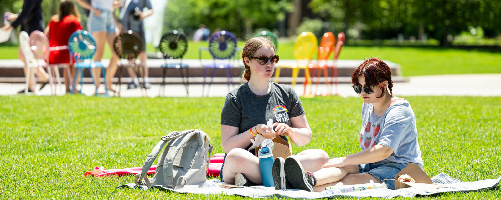 UW student Amelia Erdman (left) and A.J. Jensema (right) enjoy a boxed lunch at library mall.