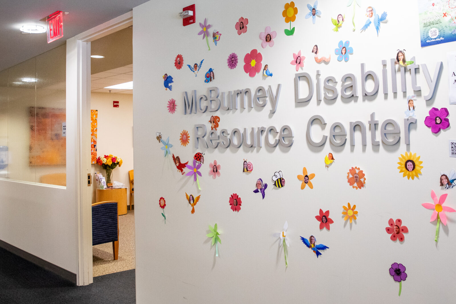 Sign outside McBurney Disability center with flowers and bird stickers around it