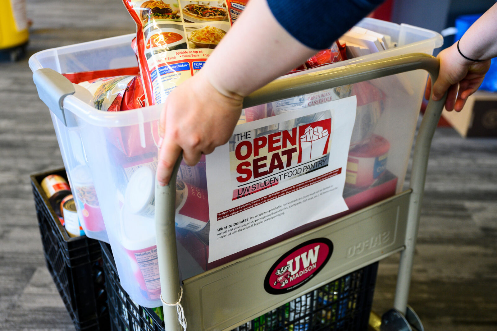 A food cart marked Open Seat loaded with dry goods groceries