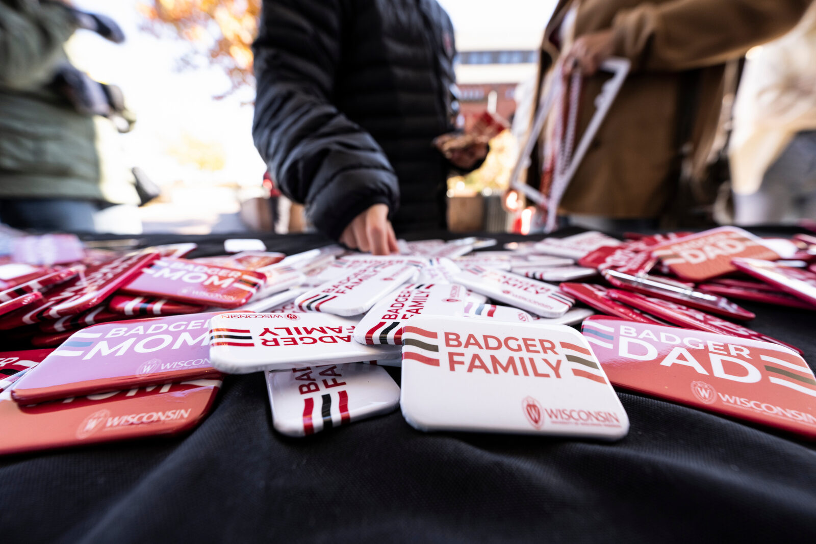 Family Weekend participants select branded buttons and other swag during a Badger Family Fest event held outside at the Memorial Union Terrace at the University of Wisconsin, Madison.