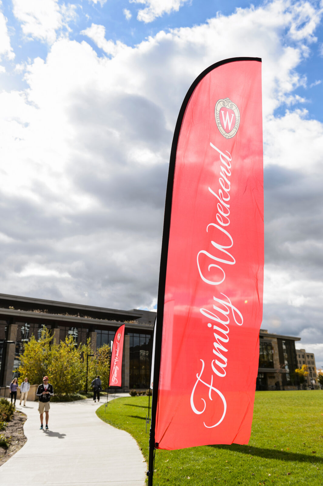 Family Weekend banners flutter in the wind as pedestrians walk to and from the Gordon Dining and Event Center.